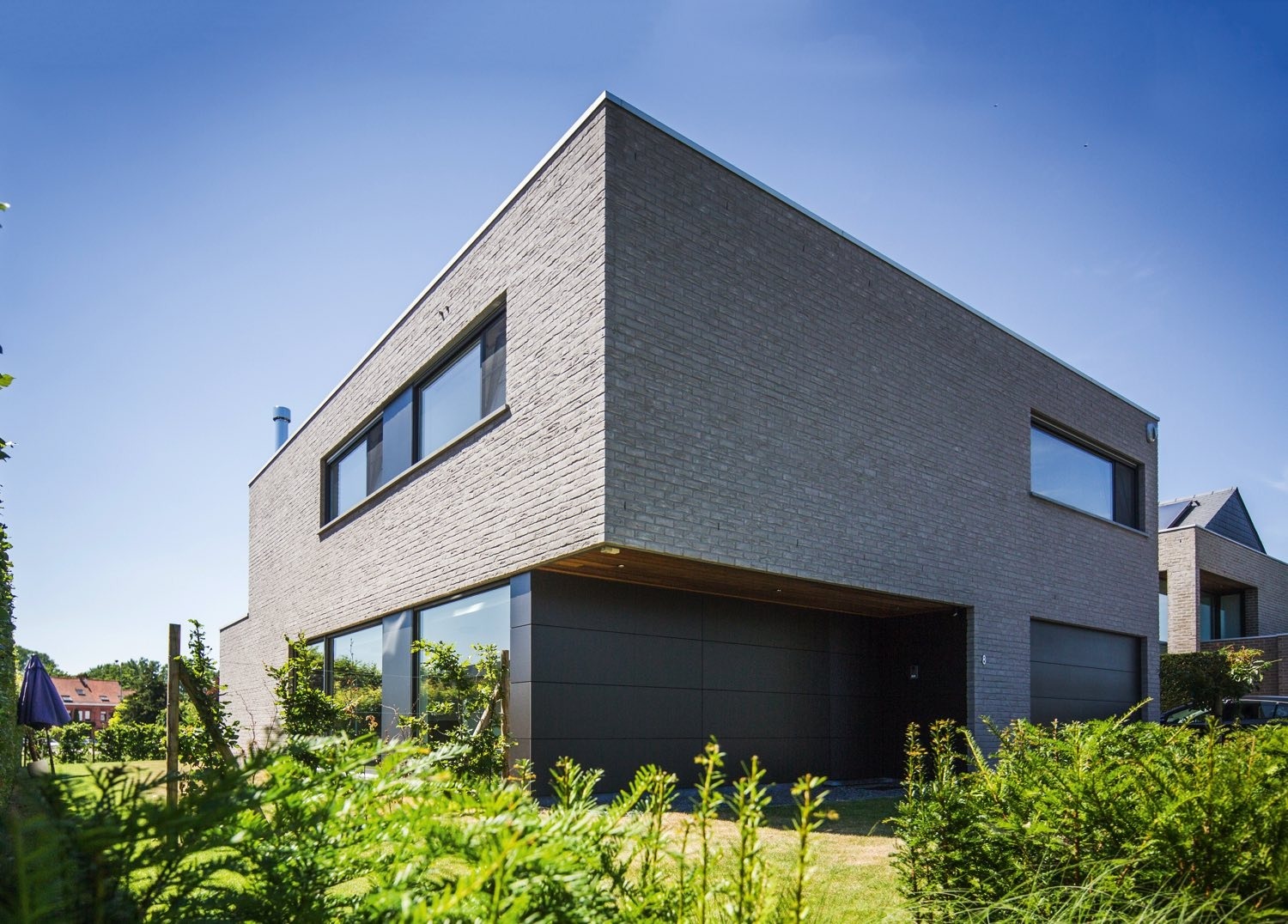 Maison moderne à ossature bois, semi-mitoyenne, brique gris, des panneaux HPL de Trespa